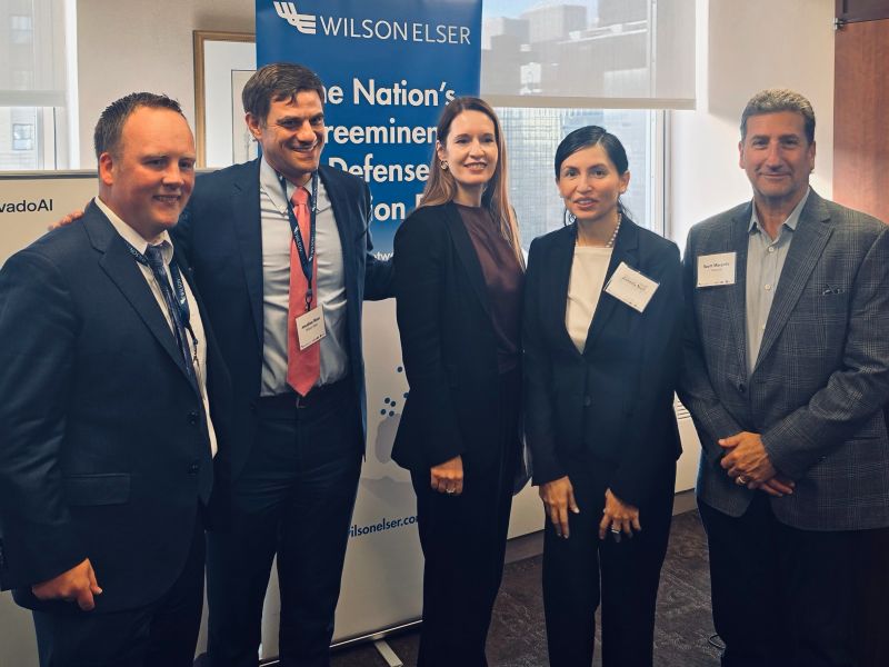 The Convergence panellists standing together in front of a Wilson Elser banner, New York City.