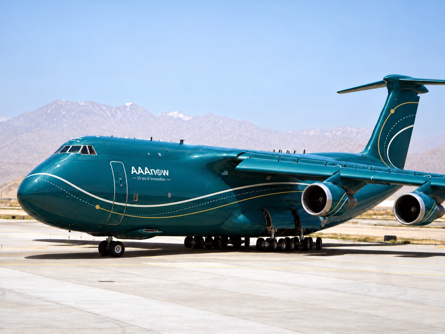 A large cargo aircraft in AAAnow teal livery on a sunlit apron, mountains behind. The AAAnow logo and 25 yrs of innovation sit behind the cockpit, and a cream line with a gold dotted line sweeps along the fuselage and up the tail.